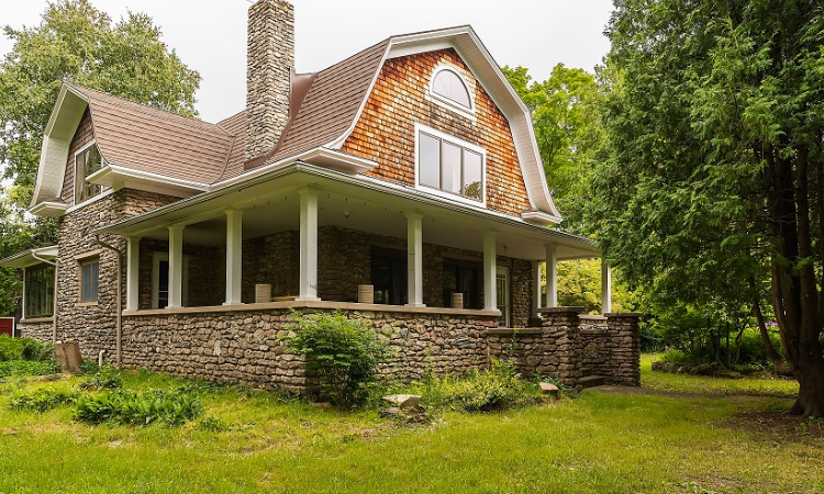 A large house with a porch and stone walls.