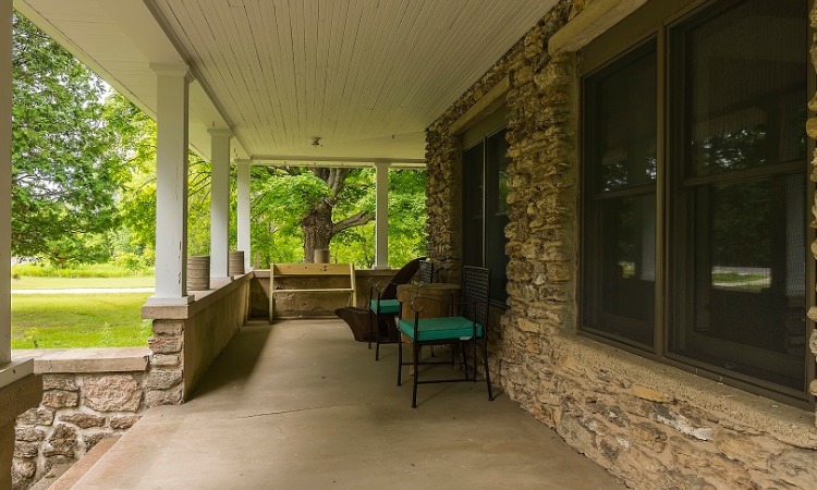 A porch with chairs and a bench on it