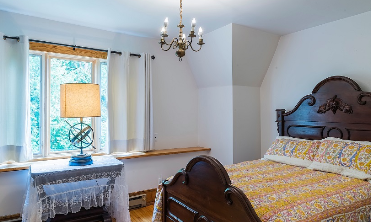 A bedroom with a bed, dresser and window.