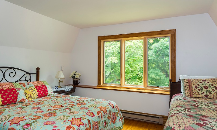 A bedroom with two beds and a large window.