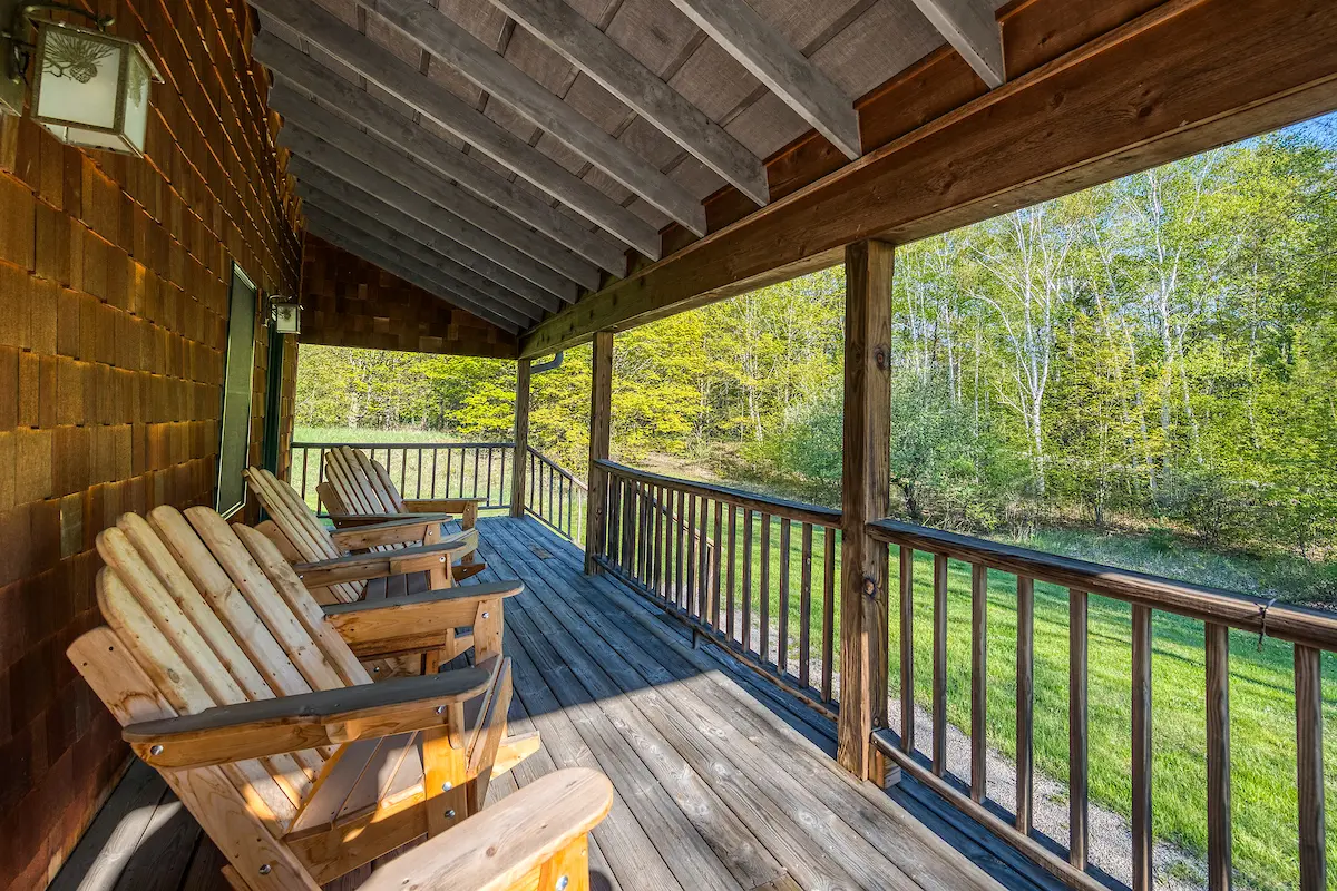 A porch with wooden chairs and benches on it.