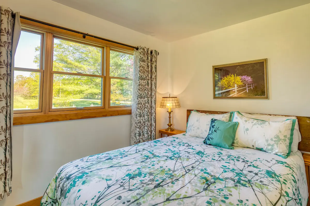 A bedroom with a bed, nightstand and window.