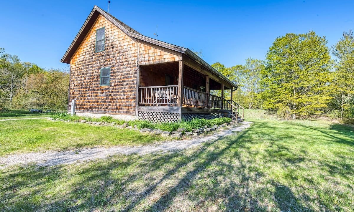 A wooden house with a porch and a stone walkway.